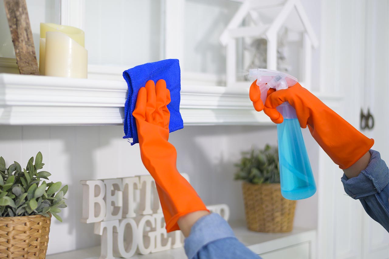 Mains avec gants en train de nettoyer une étagère